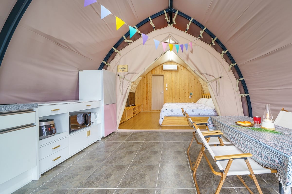Une tente confortable équipée d’un coin cuisine, d’un lit et d’un espace repas.