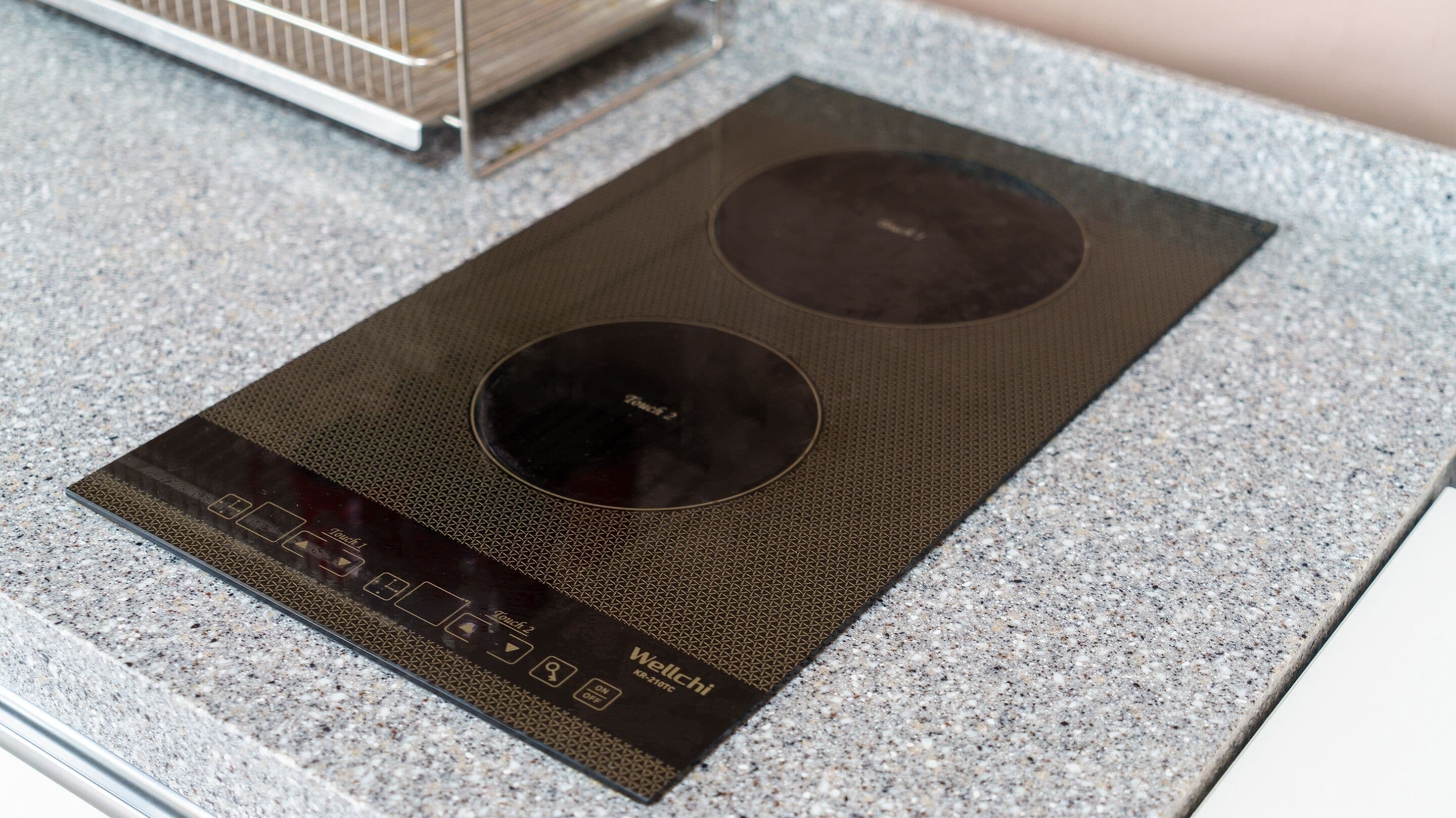 A kitchen with a touchless induction cooktop on a granite countertop.