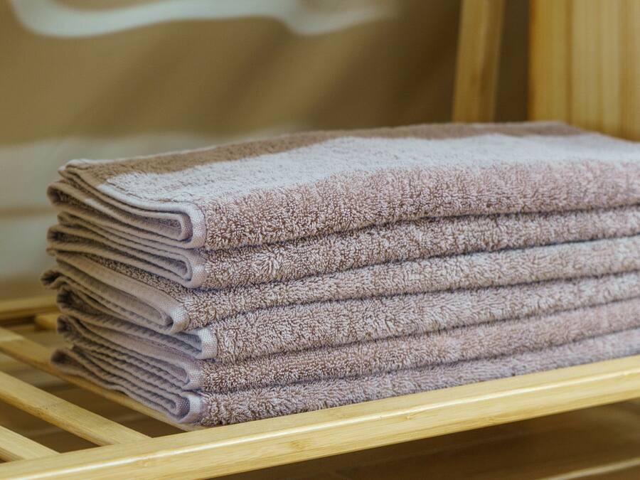 A stack of folded towels on a wooden shelf.
