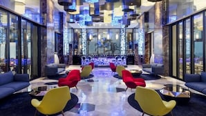 Een moderne lobby met honingraatvormige plafondpanelen, een bar in het midden en zitgedeeltes.