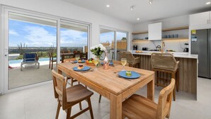 A modern kitchen with a dining area, large windows, and a view of the outdoors. - Spectacular View  Private Pool  King Beds  Ensuite (Noord)
