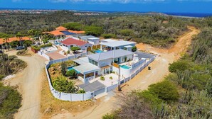 A modern house with a swimming pool, surrounded by a natural landscape and a dirt road. - Spectacular View  Private Pool  King Beds  Ensuite (Noord)