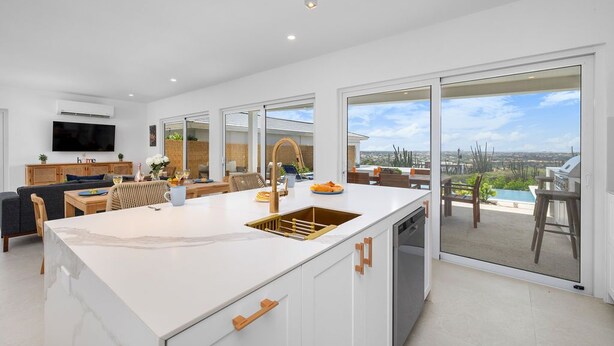 A modern kitchen with a large island, a dining area, and a view of the outdoors. - Spectacular View  Private Pool  King Beds  Ensuite (Noord)