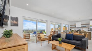A spacious living area with a sofa, coffee table, and chairs, a kitchen area, and large sliding glass doors leading to an outdoor terrace with a pool. - Spectacular View  Private Pool  King Beds  Ensuite (Noord)
