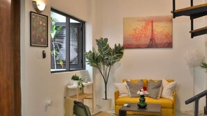 Una sala de estar con un sofá amarillo, una mesa de centro y una planta.