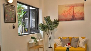 Una sala de estar con un sofá amarillo, una mesa de centro, una planta y un cuadro de la Torre Eiffel.
