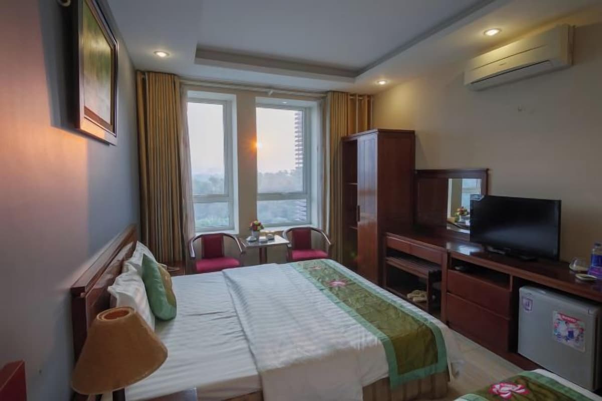 A hotel room with a bed, a television, a desk, and a chair.