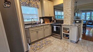 A kitchen with a central island, stainless steel appliances, and a view into the dining area.