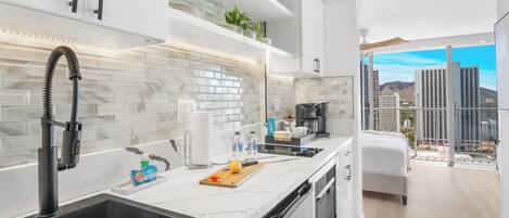 A modern kitchen with a black sink, white cabinets, and a marble backsplash.