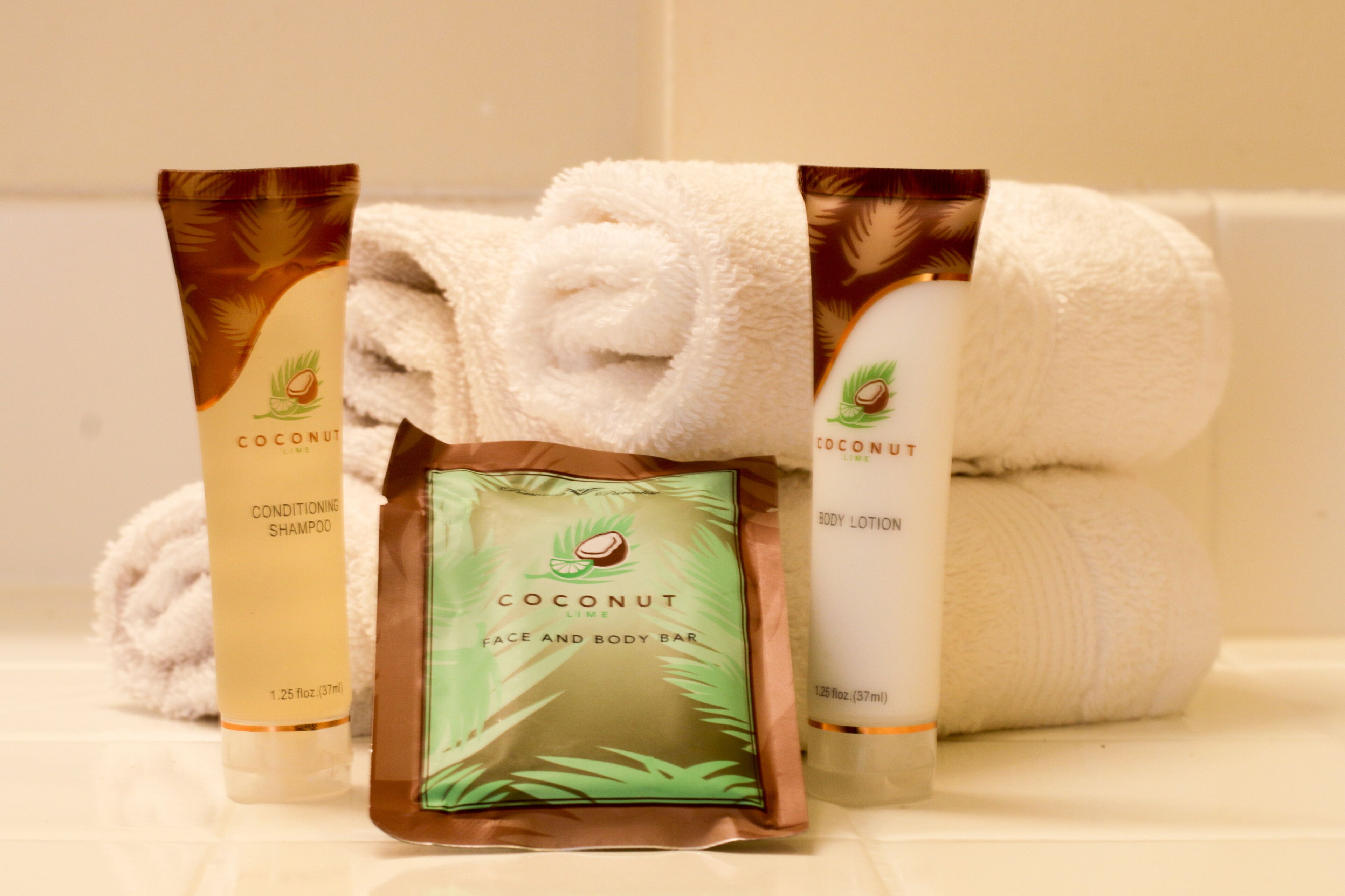 A bathroom with toiletries including a coconut body lotion, a face and body bar, and a shampoo.