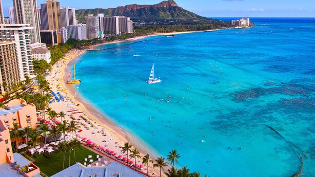Un paysage urbain côtier avec une plage, des immeubles de grande hauteur et une vue dégagée sur l’océan.