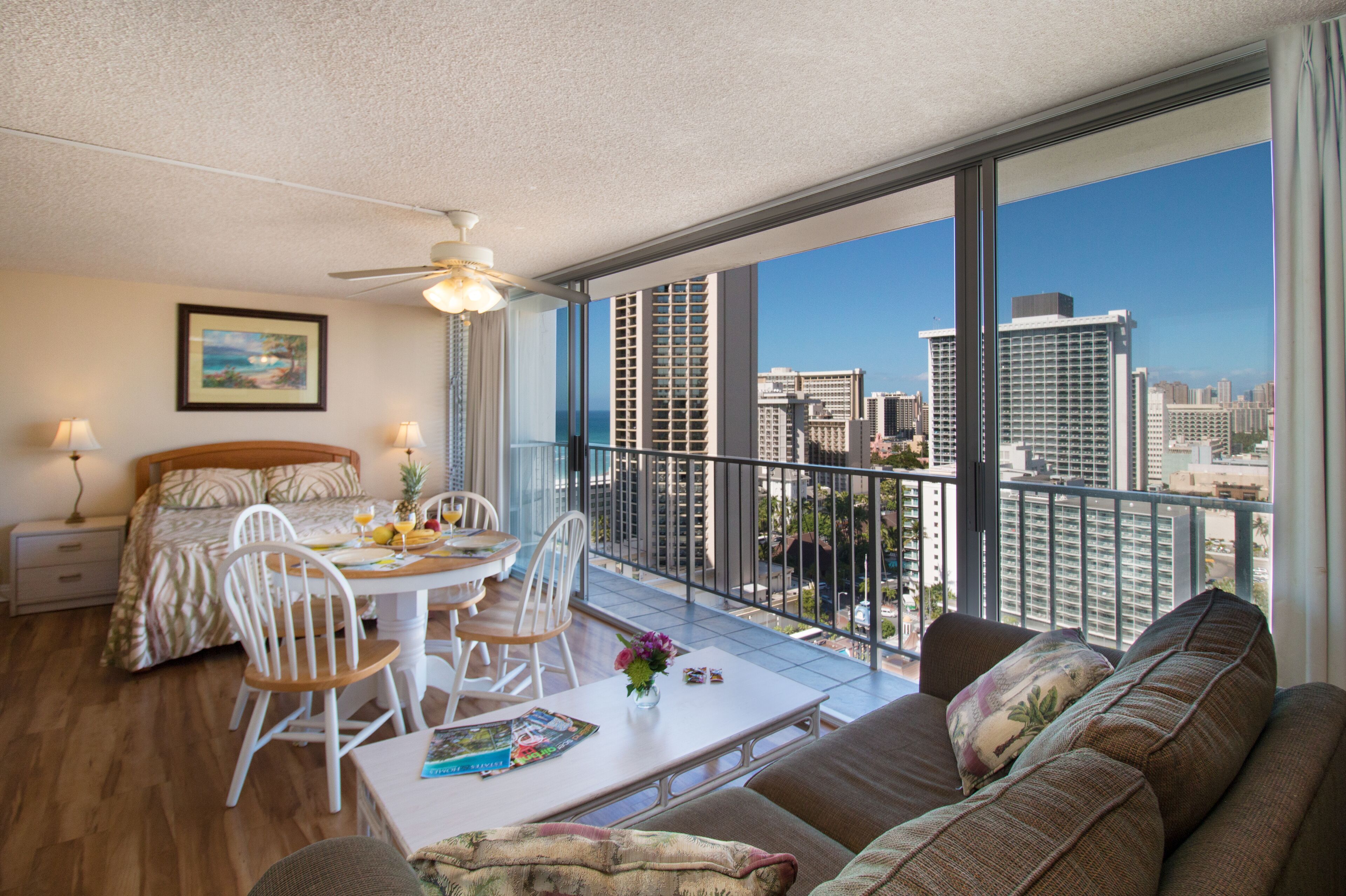 Ein modernes Hotelzimmer mit Balkon, einem Essbereich und einem Bett mit Blick auf die Stadt.