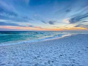 A beach with white sand and a view of the ocean.