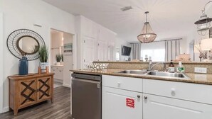 Une cuisine moderne avec des meubles blancs, un lave-vaisselle en acier inoxydable et un plan de travail en granit.