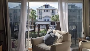 Un balcon donnant sur un immeuble blanc, avec une table ronde et un canapé beige.