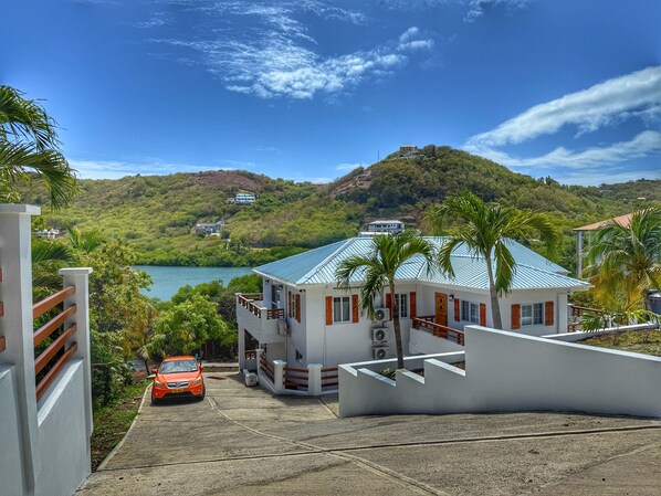 A modern building with a blue roof, surrounded by lush greenery and a view of a lake. - Harbor Haven Luxury Retreat I- VEHICLE INCLUDED (St. George)