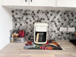 Eine Küche mit Kaffeemaschine, einer Gewürzregal und einer rückwand mit Muster.