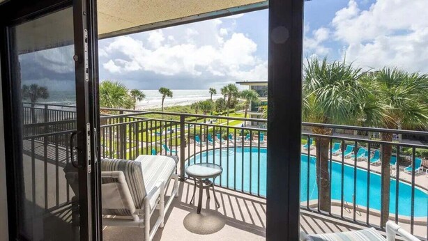 A balcony with a view of a swimming pool and beach.