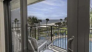 A balcony with a view of a pool and the ocean.