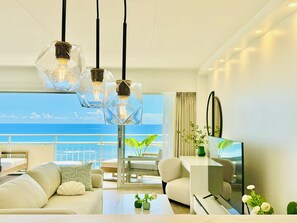 Habitación de hotel moderna con balcón, sofá, mesa de centro y televisor.