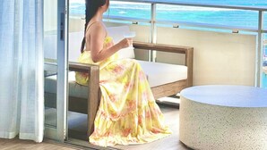 A room with a large window overlooking the ocean, a wooden bench, and a round table. - Panoramic Oceanview Home (Car Available) (Honolulu)