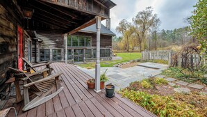 A wooden cabin with a porch, potted plants, and a stone pathway. - Renovated Grand Woodstock Barn (Bearsville)