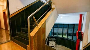 A staircase with a wooden handrail and black steps, leading to a lower level. - Glitz Hotels AR Residency (Thane)