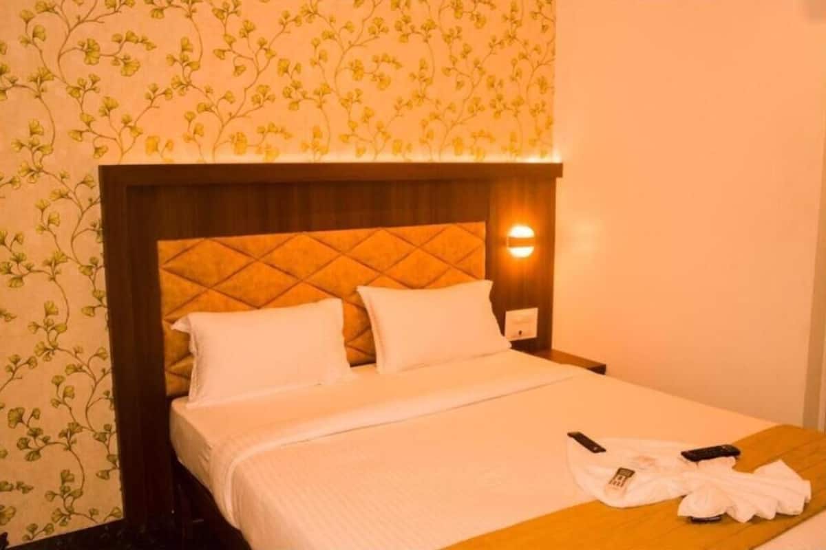 Een hotelkamer met een bed, nachtkastje en een wandlamp.