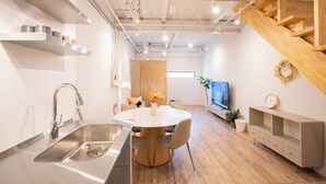 A modern kitchen with a stainless steel sink, wooden dining table, and a built-in wooden staircase. - REPOS tsuruhashi (Osaka)