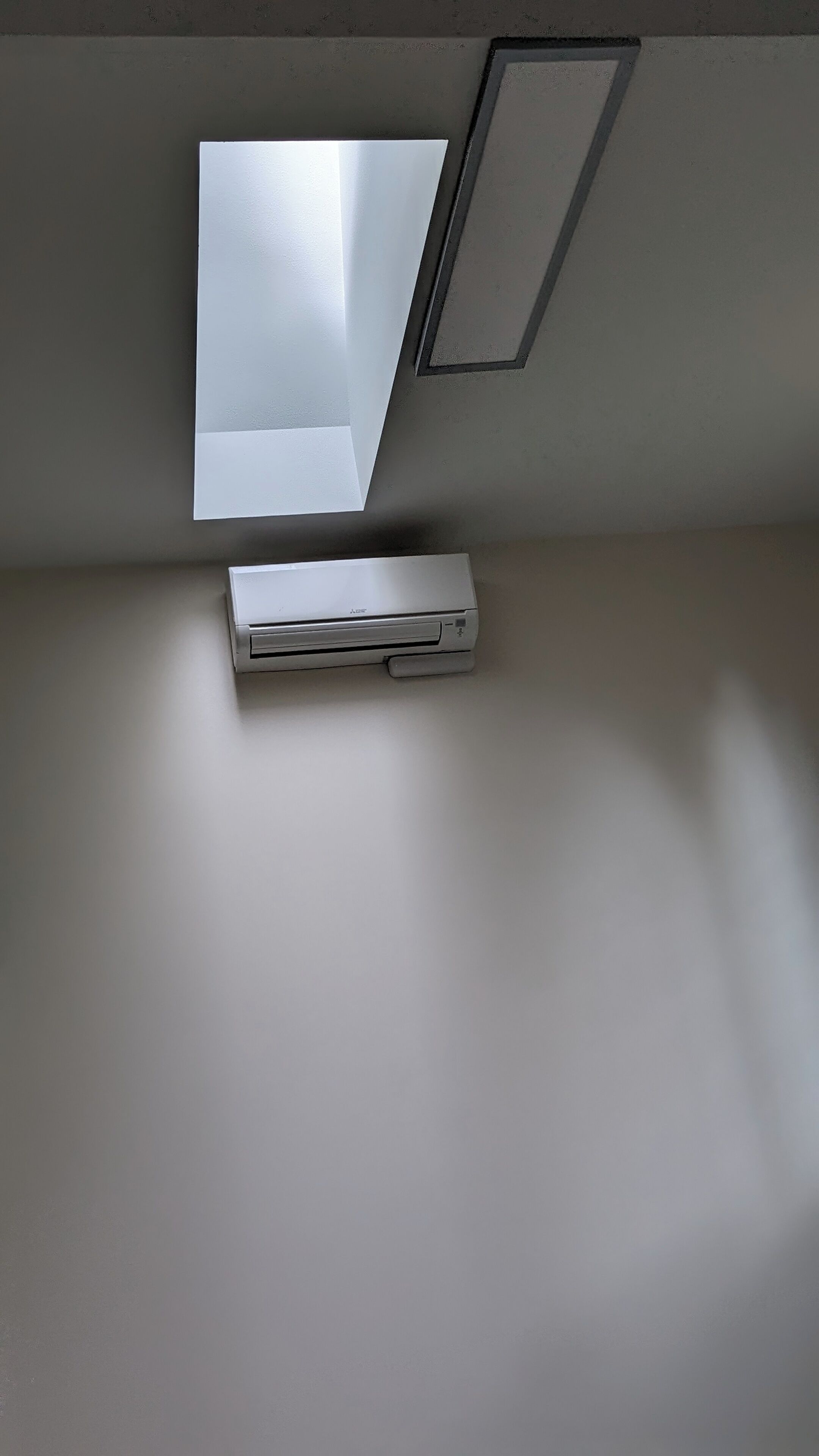 A ceiling with a recessed light fixture and a flat-screen TV mounted on the wall.