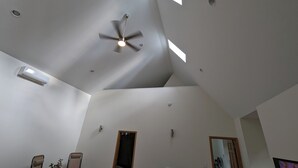 Una habitación amplia con ventilador de techo, iluminación empotrada y un gran ventanal que proporciona luz natural.
