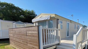 Une maison mobile dotée d’une terrasse en bois et d’un petit escalier menant à une porte.