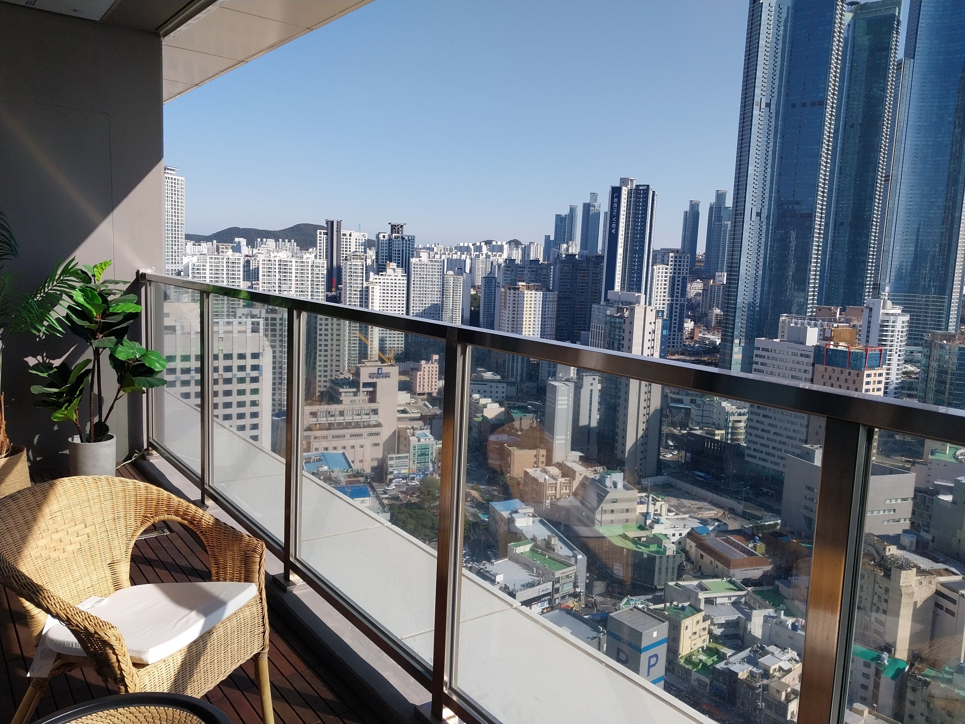 A balcony with wicker furniture and a view of a cityscape with tall buildings.
