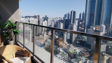 A balcony with wicker furniture and a view of a cityscape with tall buildings.