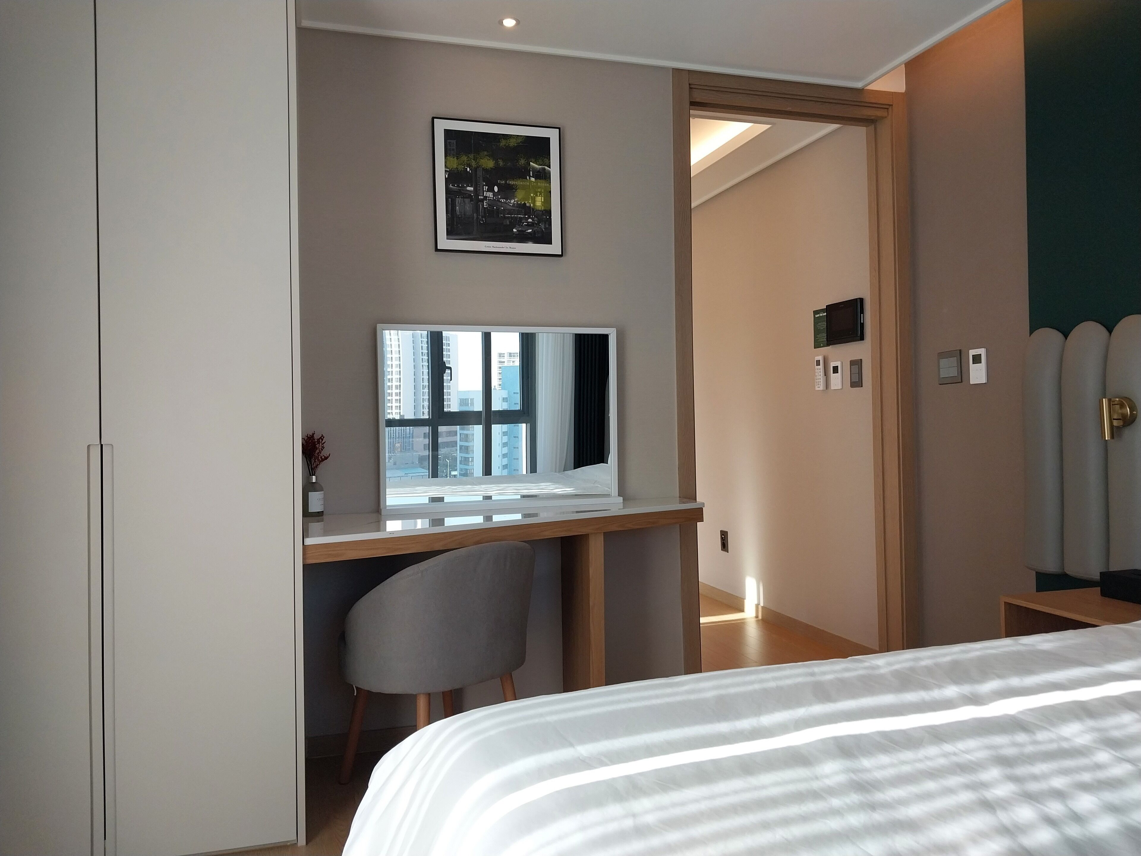 Um quarto moderno com cama, escrivaninha com computador, cadeira e um quadro na parede.