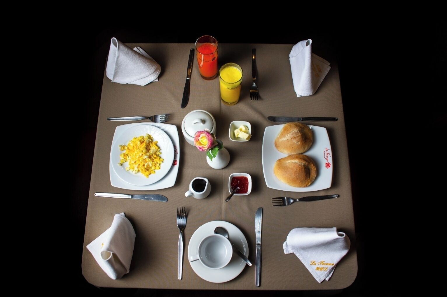 Ett välordnat frukostbord med tallrikar fyllda med äggröra, rostat bröd och en liten blomsteruppsättning.