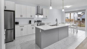 A modern kitchen with white cabinets, stainless steel appliances, and a large island.