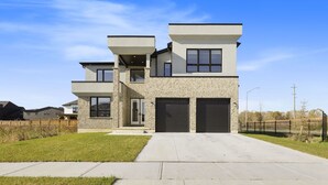 A modern two-story house with a flat roof, a stone facade, and a front garage.