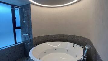 A modern bathroom with a freestanding bathtub, a round mirror, and a built-in shower.