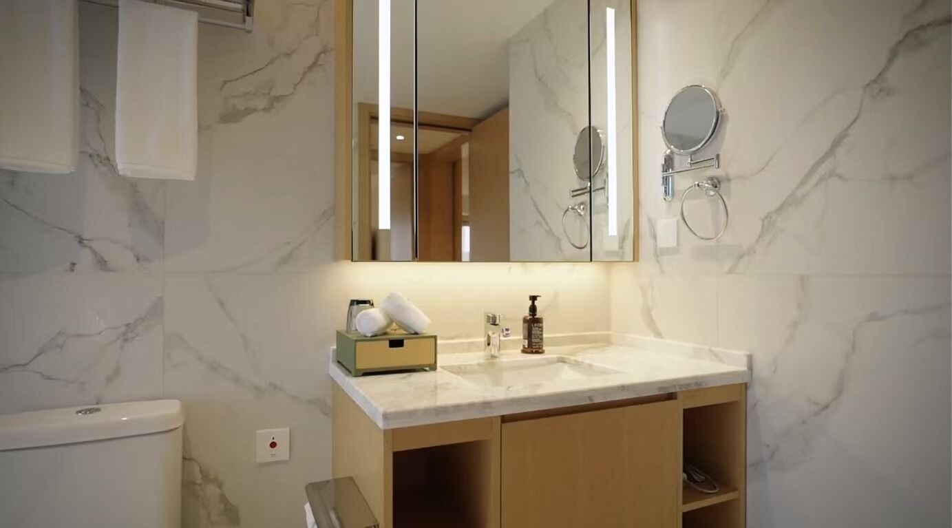 A bathroom with a marble countertop, a large mirror, a towel rack, and a toilet.