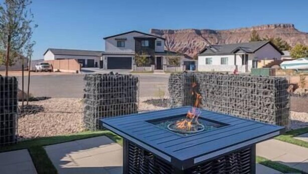 A modern outdoor patio area with a built-in fire feature, surrounded by a metal fence. - Zion Modern Lux Casita (Virgin)