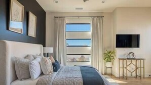 A modern bedroom with a large bed, a TV, and a view through the window. - Zion Modern Lux Casita (Virgin)