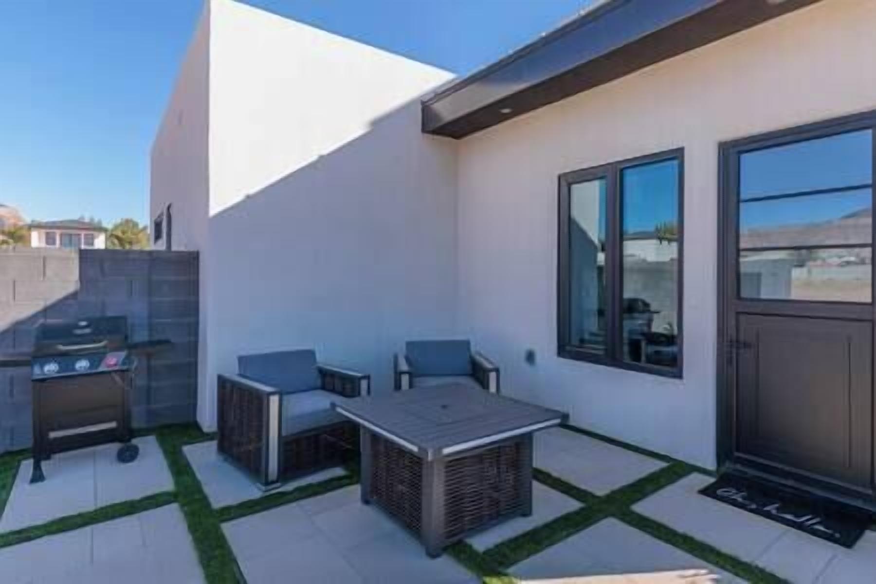 Un patio moderno al aire libre con una parrilla, dos sillas y una mesa.