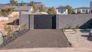 A residential area with a paved driveway leading to a gated entrance. - Zion Modern Lux Casita (Virgin)