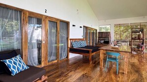 Une pièce spacieuse avec un plancher en bois, un canapé agrémenté d’un coussin à motifs, une petite table et une chaise.