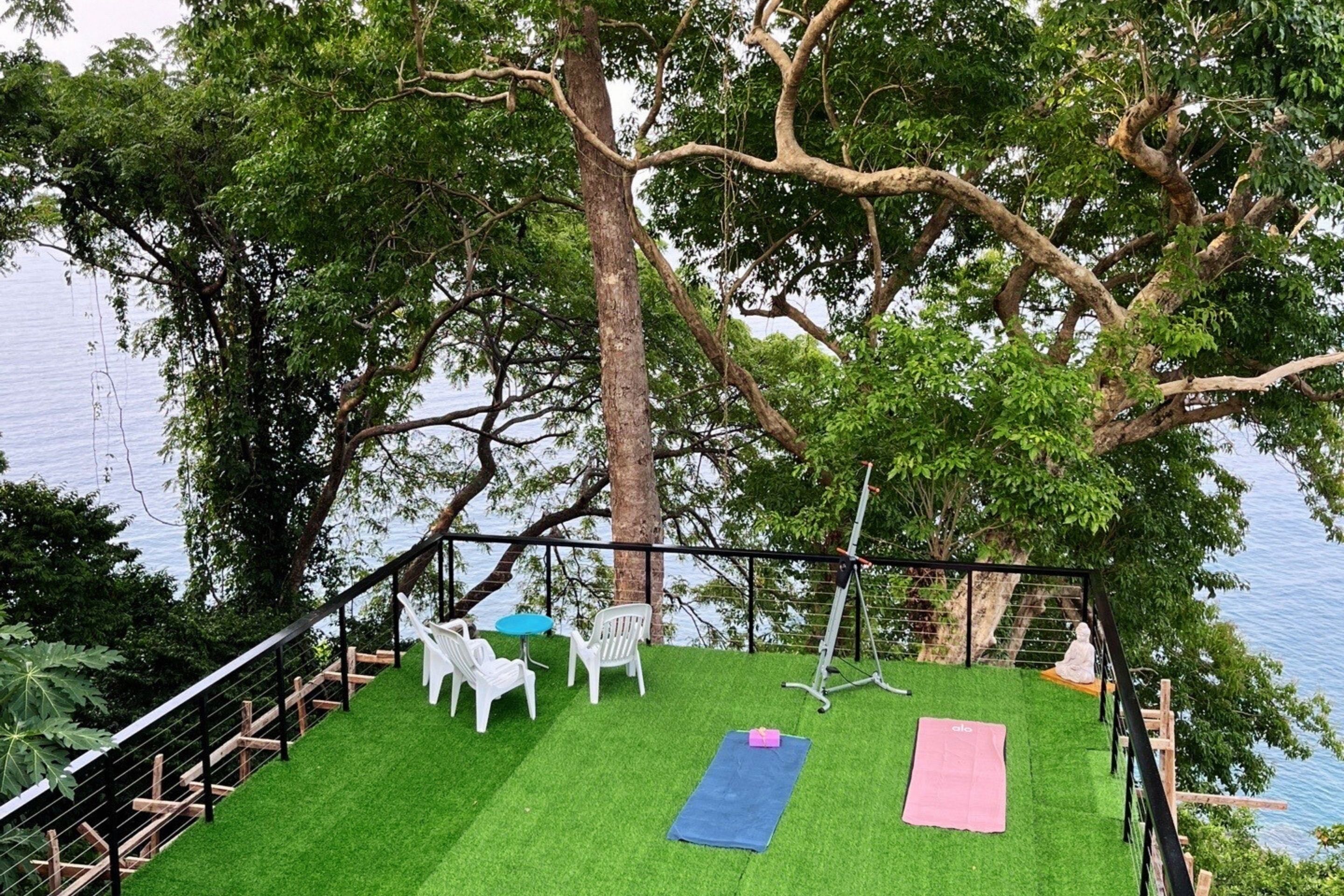 A deck with artificial grass, exercise equipment, and outdoor seating by a body of water.