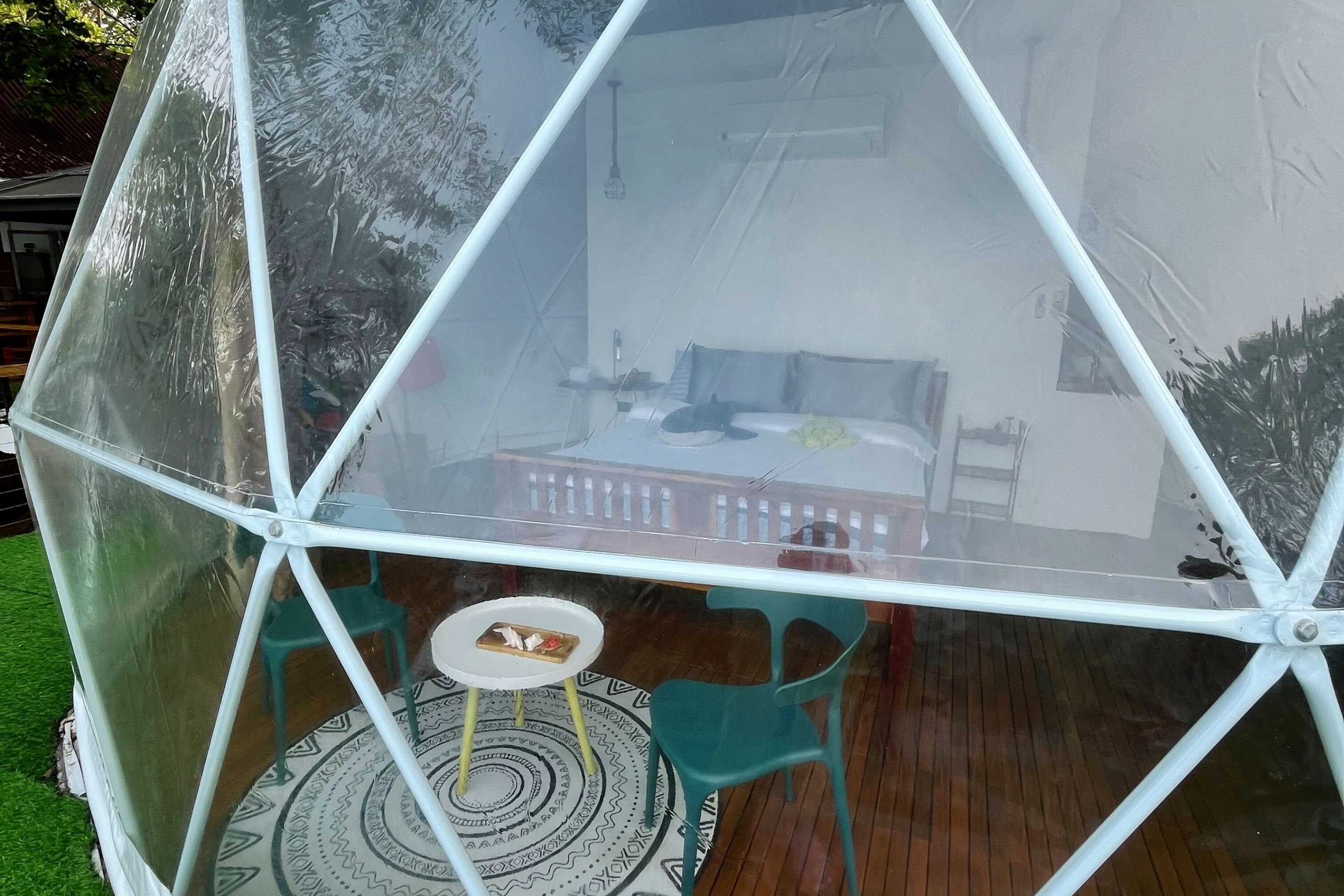 A transparent geodesic dome structure with a table and chairs inside.