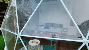 A transparent geodesic dome structure with a table and chairs inside.