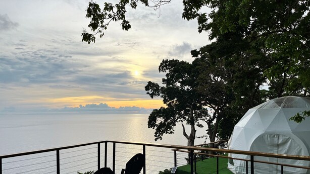 Un balcon avec vue sur la mer, une tente blanche et une chaise.