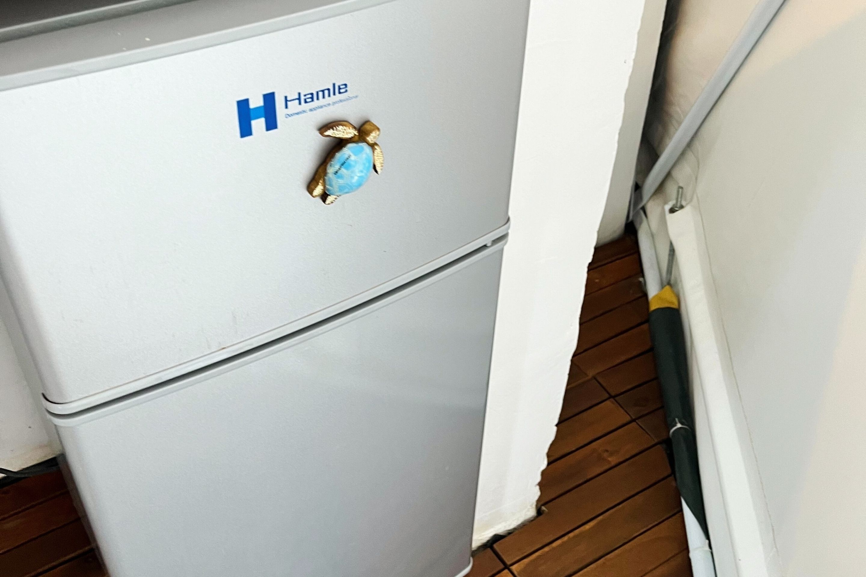 Ein weißer Kühlschrank mit einem blauen und goldenen Aufkleber obenauf.